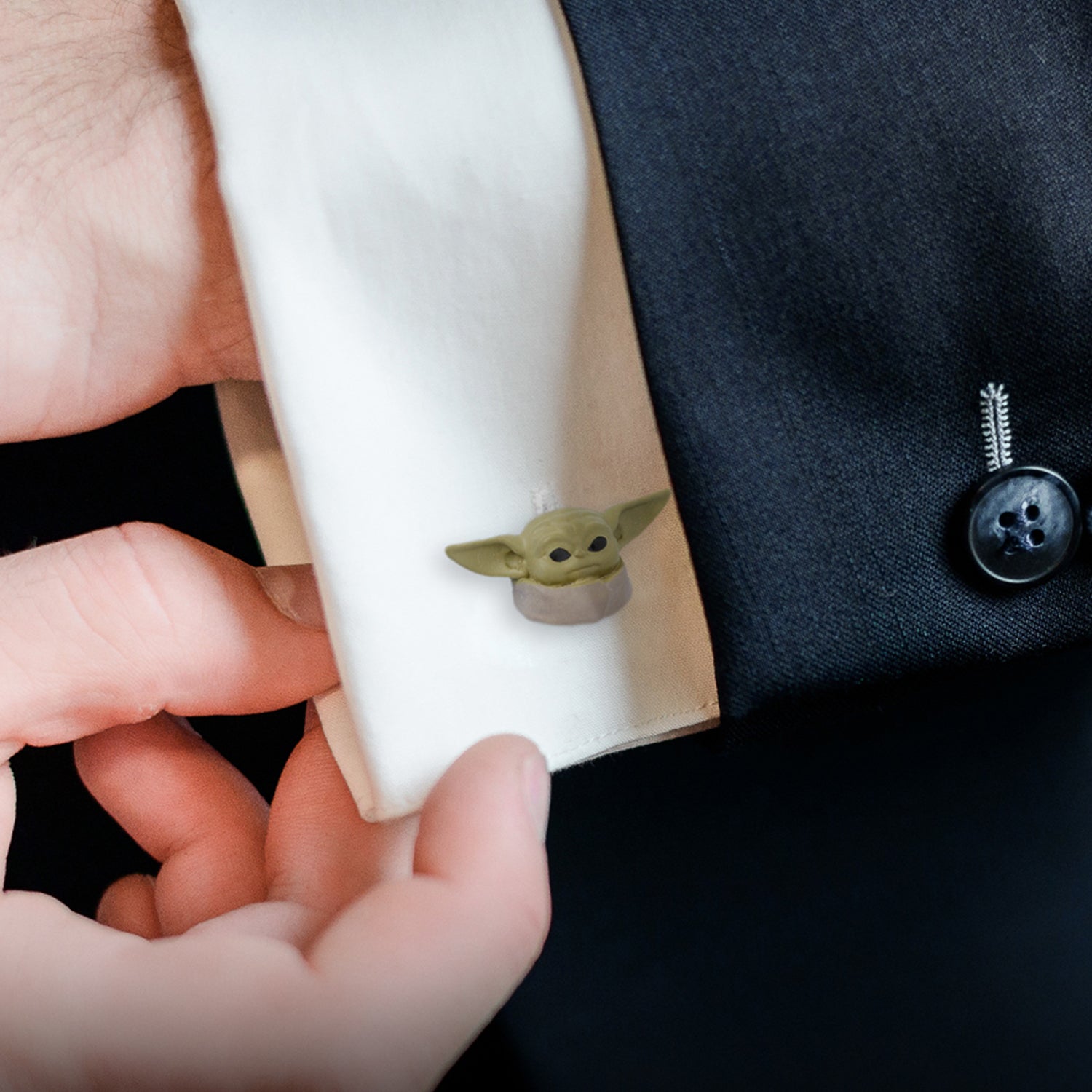 Side profile of the plated metal Grogu cufflink showing the sculpt thickness.